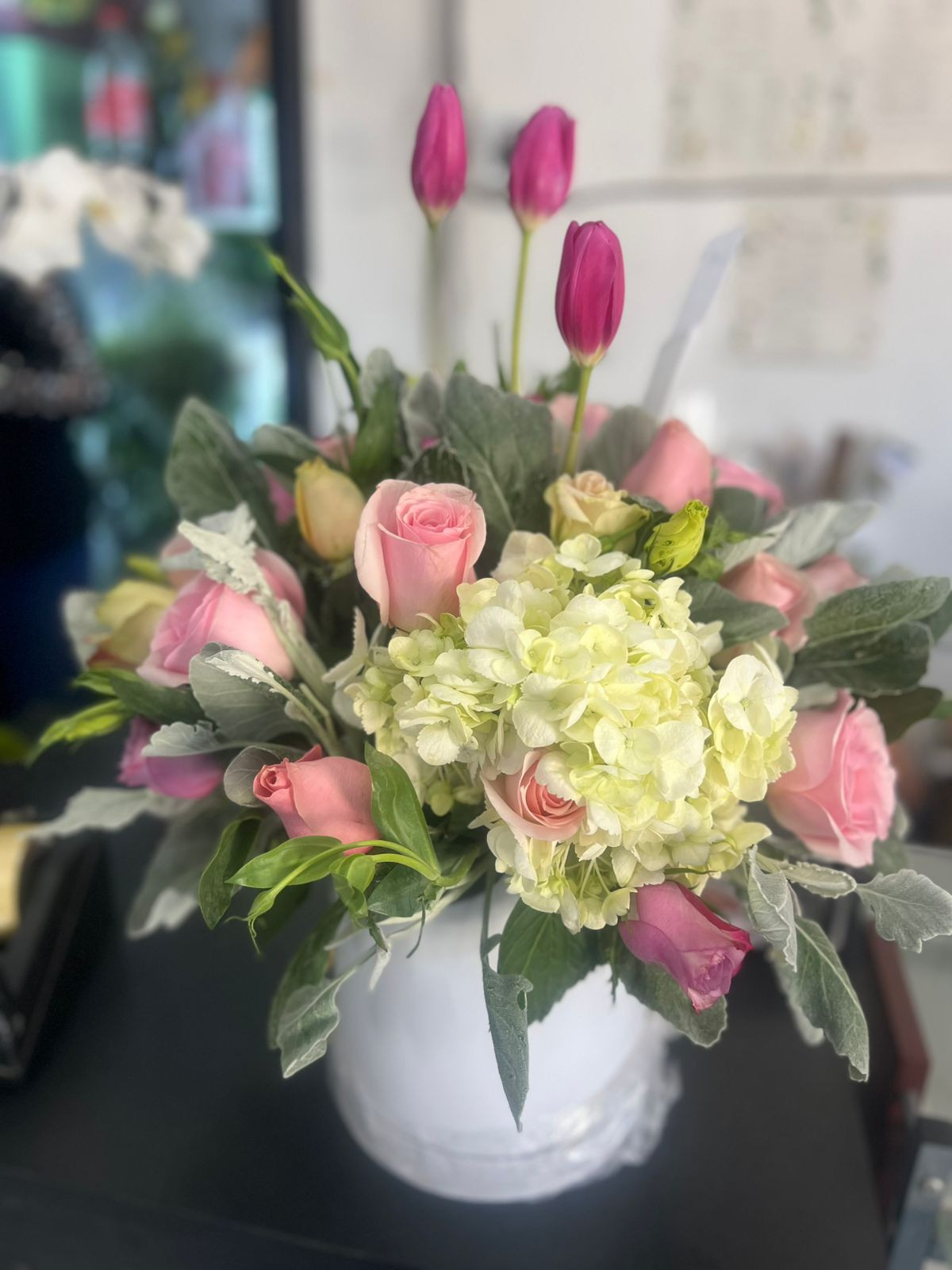 ARREGLO  FLORAL  CON  ROSAS TULIPANES  Y  FOLLAJES  FINOS  EN BASE  BLANCA  DE C ERAMICA